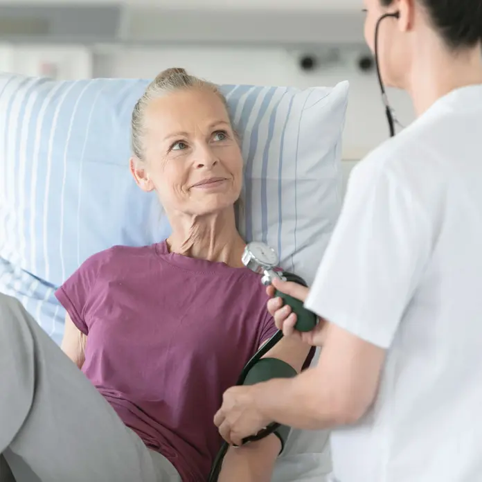 Eine Mitarbeitende des Klinikums misst Blutdruck bei einer Patientin.