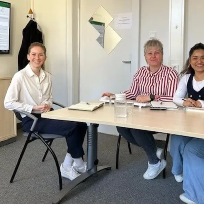 Drei Frauen sitzen in einem Besprechungszimmer und erarbeiten die Schulungen.