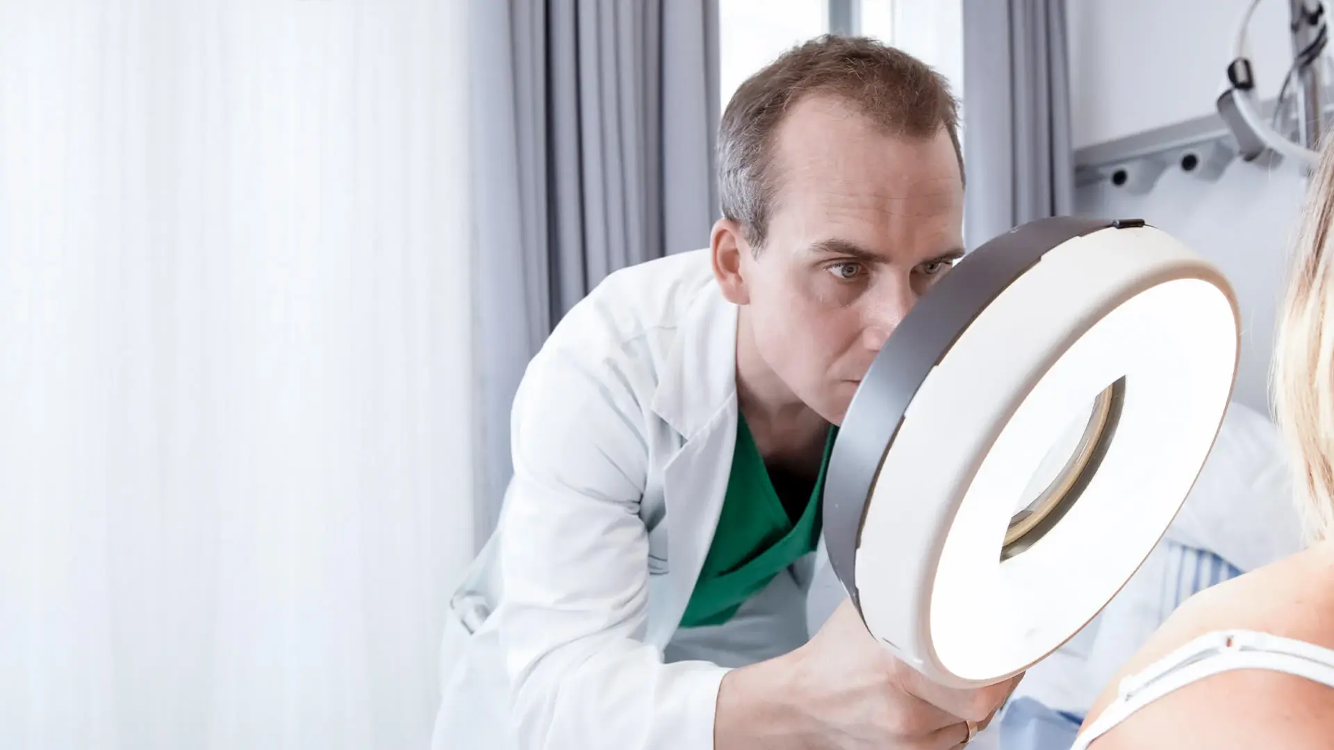 Ein Mitarbeiter untersucht die Haut am Rücken einer Patientin. 