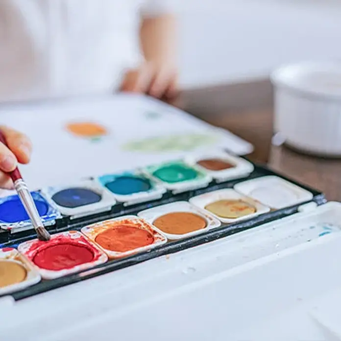 Ein Kind malt mit Wassermalfarben. 