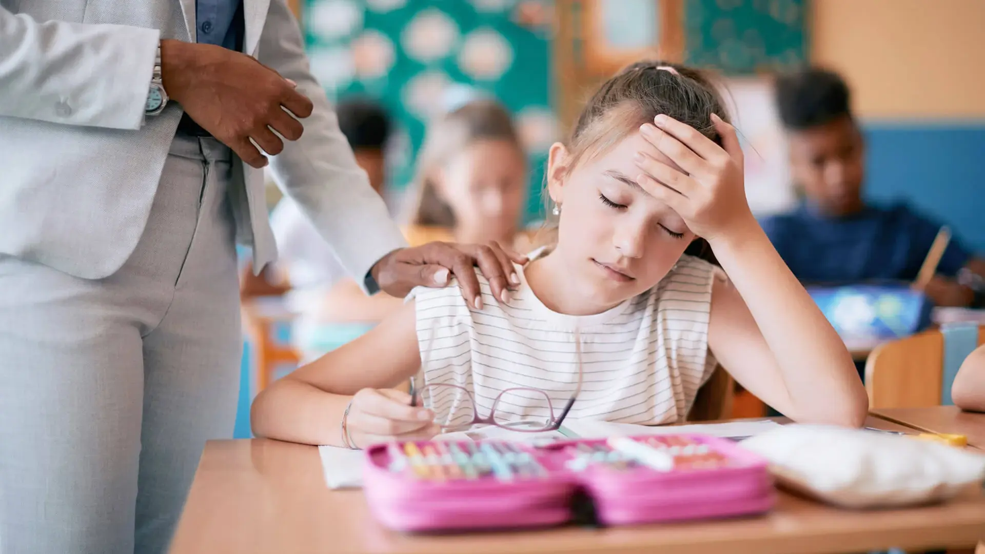 Kind sitzt im Klassenzimmer mit Kopfschmerzen