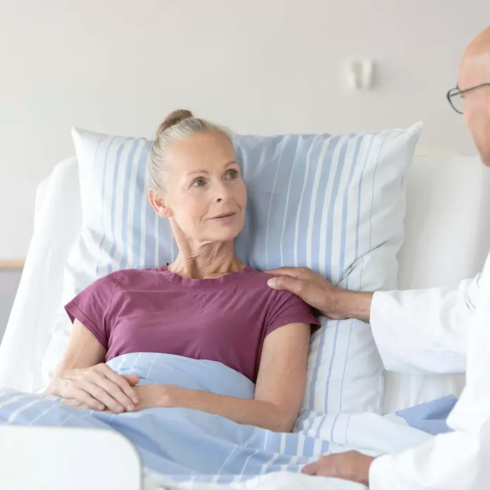 Arzt spricht mit Patientin im Bett
