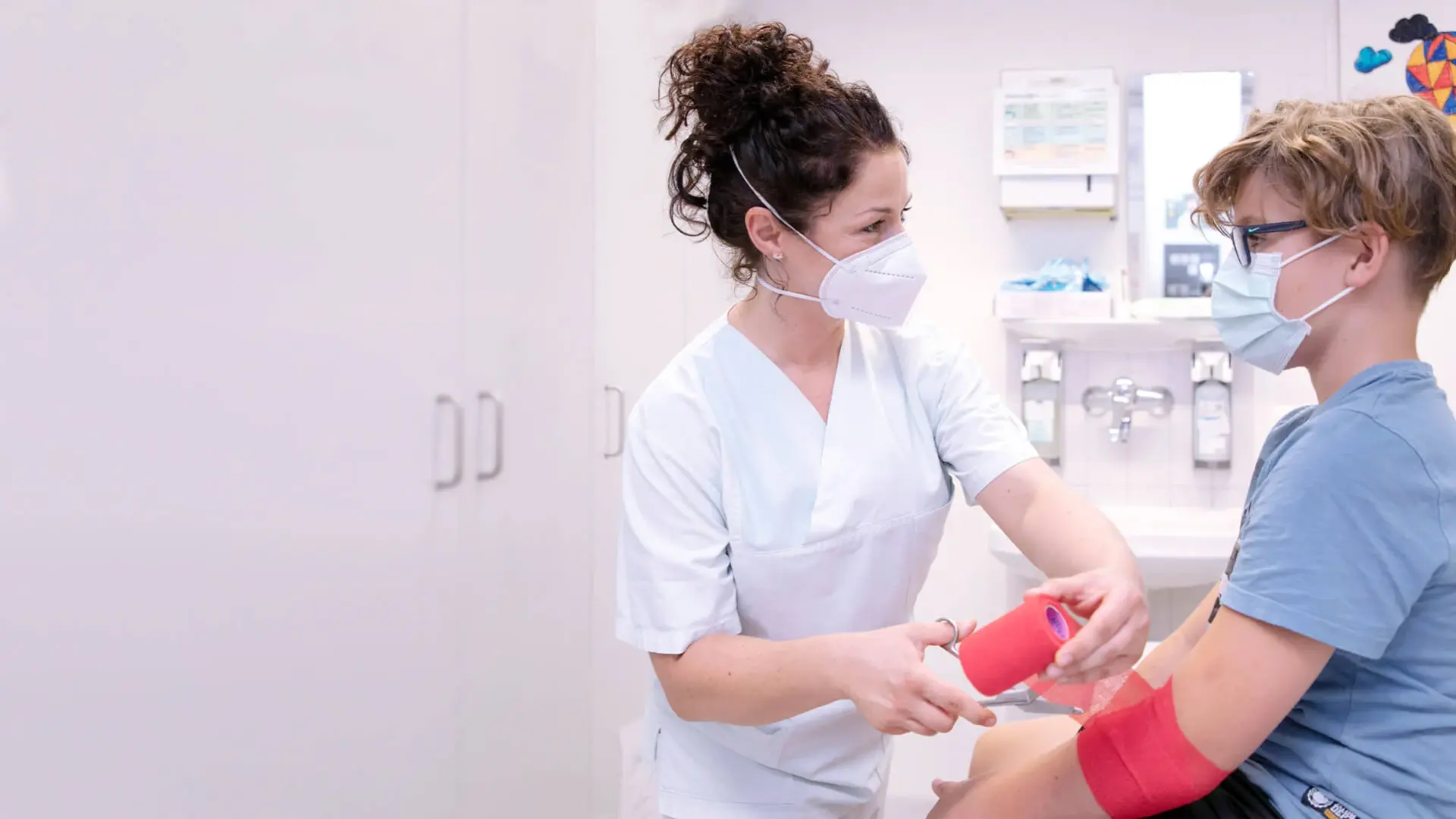 Medizinische Pflegekraft verbindet den Arm eines Kindes in der Kinder Notaufnahme