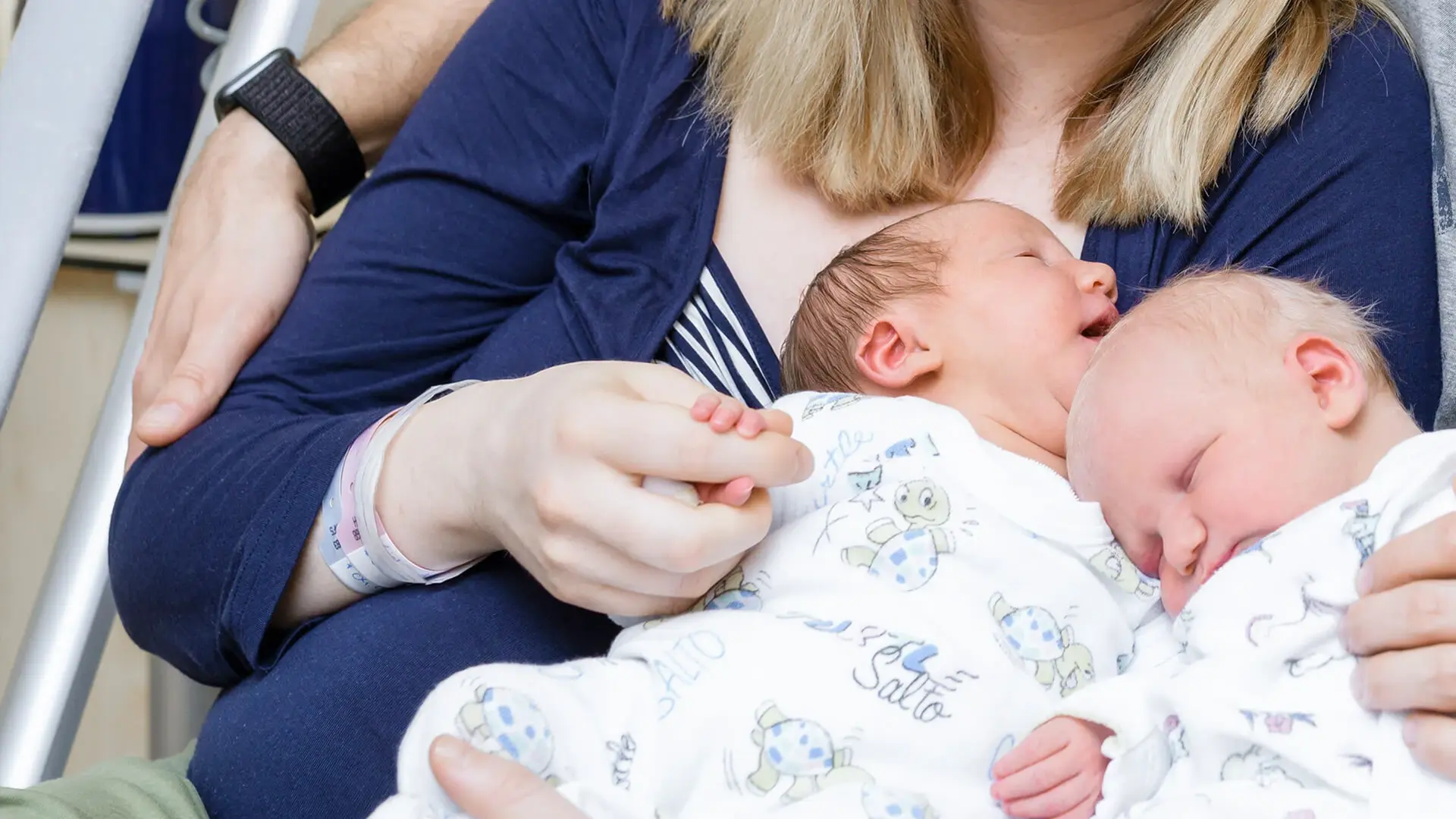 Neugeborene Zwillinge in den Armen der Mutter