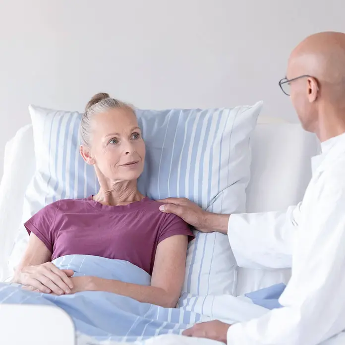 Ein Arzt spricht mit einer Patientin im Bett. 