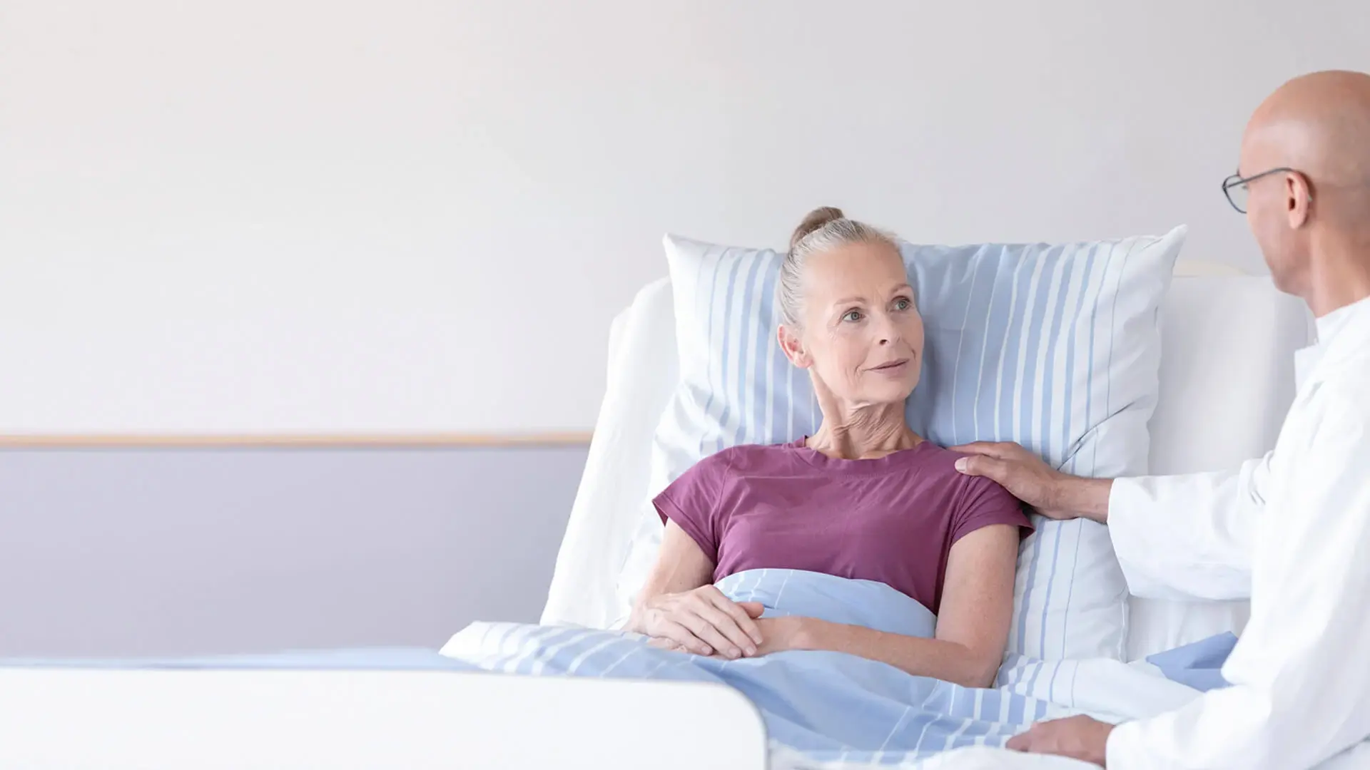 Ein Arzt spricht mit einer Patientin im Bett. 