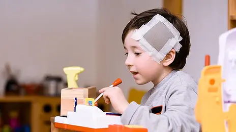Der damals 5-jährige Giovanni spielt in der Kinderklinik. Er hat ein großes Pflaster am Kopf. 