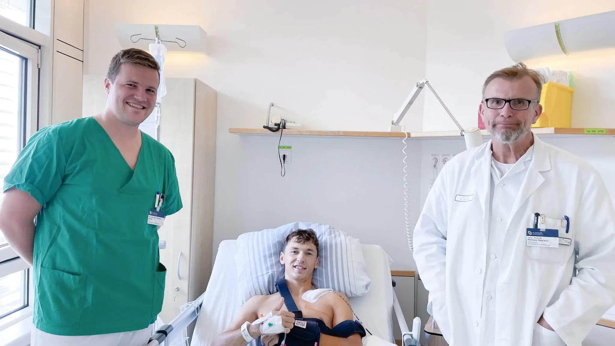 Club-Profi Benjamin Goller liegt im Bett. Ein Assistenzarzt und der Chefarzt stehen daneben. 