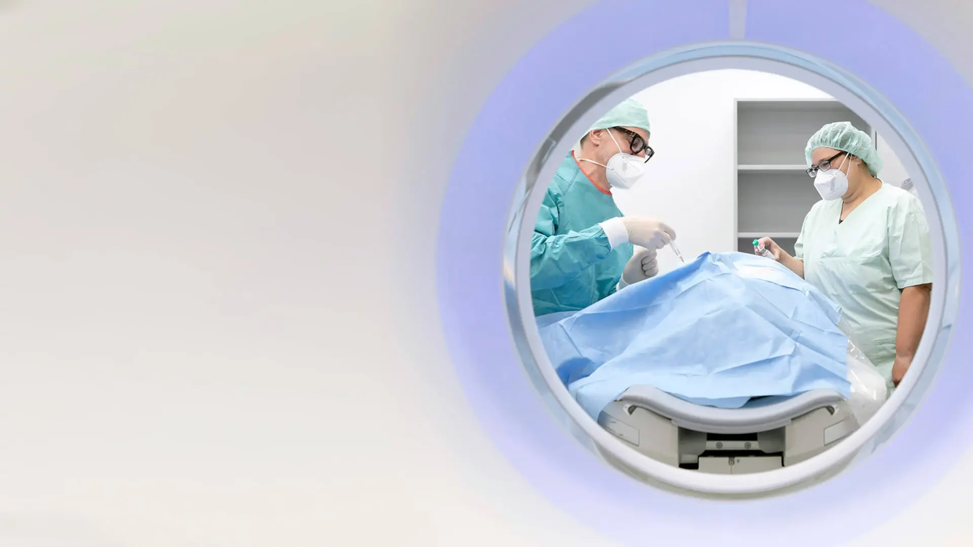 Zwei Mitarbeitende der Neuroradiologie sprechen während der Untersuchung mit einem Patienten. 