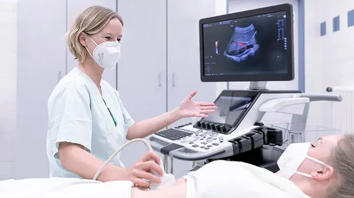 Eine Mitarbeiterin der Gastroenterologie untersucht den Bauch einer Patientin mittels Ultraschall. 