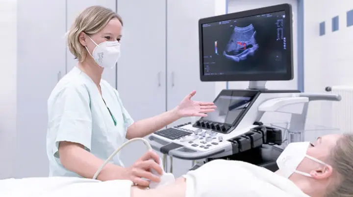 Eine Mitarbeiterin der Gastroenterologie für eine Ultraschalluntersuchung am Bauch eines Patienten durch.