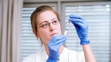 Dr. Katharina Ackermann, Fachärztin, bereitet eine Spritze vor.  