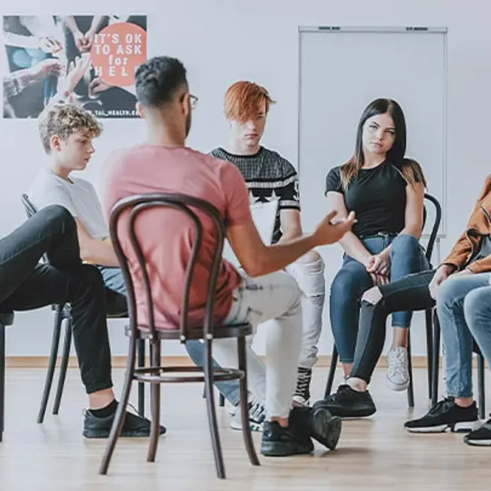 Junge Erwachsene sitzen im Rahmen einer Gruppentherapie zusammen. 
