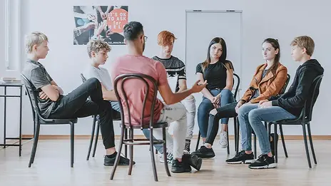 Junge Erwachsene sitzen im Rahmen einer Gruppentherapie zusammen. 