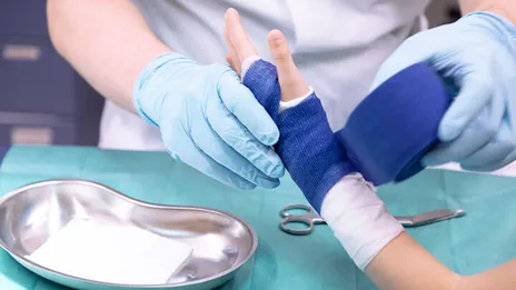 Medizinisches Personal vergipst die Hand eines Kindes