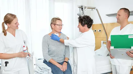 Eine Ärztin und zwei Pflegekräfte versorgen eine Patientin nach ihrer Schilddrüsen-Operation